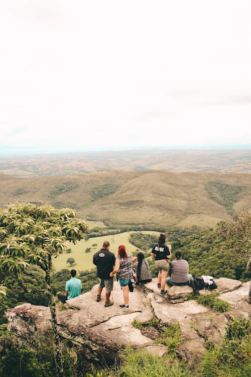 Free People Sitting and Standing on the Edge If Cliff Stock Photo