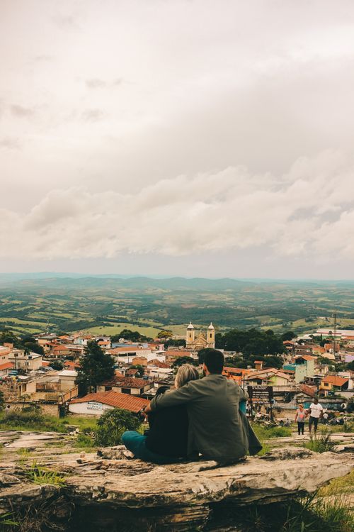 Free A couple sits embracing, overlooking the picturesque town of São Tomé das Letras, Brazil. Stock Photo