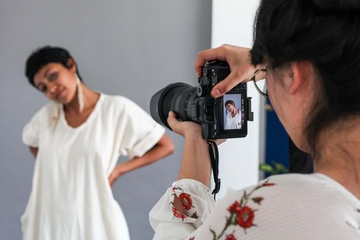 Capturing a creative fashion photoshoot with a digital camera in a studio.