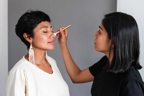 A Makeup Artist Applying Makeup on a Woman