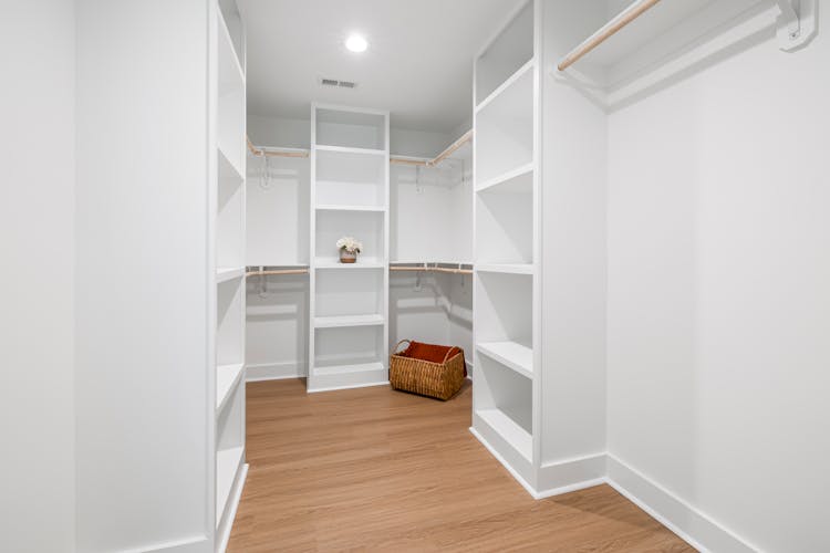 A Room With White Cabinets And Shelves With Wooden Flooring 