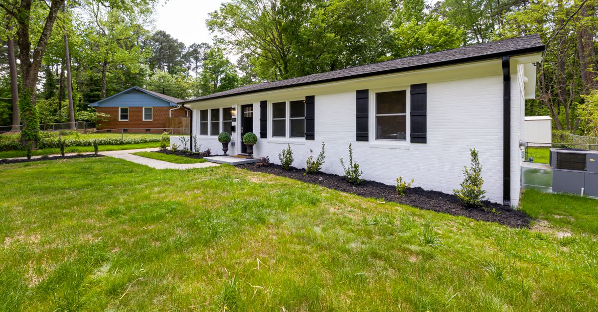 A modern suburban home with a lush green lawn and landscaped garden.