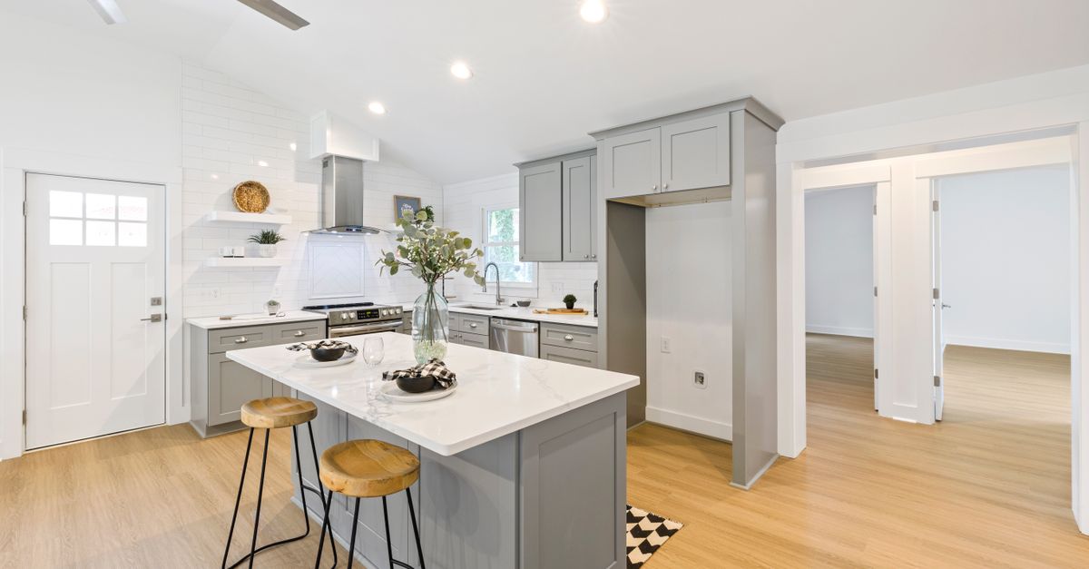 Bright kitchen interior featuring a marble island and wooden stools with minimalist design.