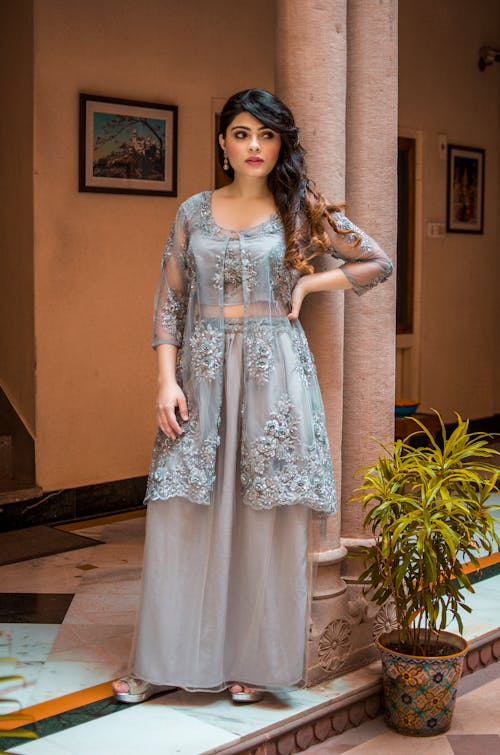 A Woman in Gray Floral Sheer Dress Standing Near Columns