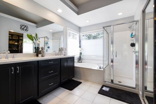 Free Sleek bathroom featuring black cabinets, glass shower, and natural light. Stock Photo