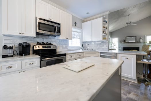 Spacious modern kitchen featuring sleek white cabinets and marble countertops, perfect for a stylish home.