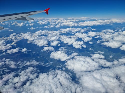 A Gray Airplane Flying Above White Clouds