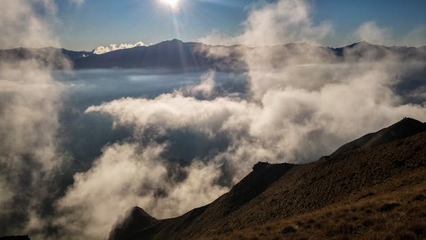 Breathtaking view of mountains and clouds in Wanaka, New Zealand, under a bright sun.
