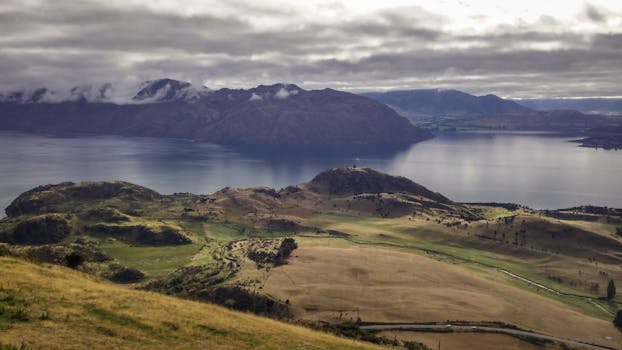 Breathtaking landscape of Lake Wanaka with its lush surrounding hills and cloudy sky in New Zealand.