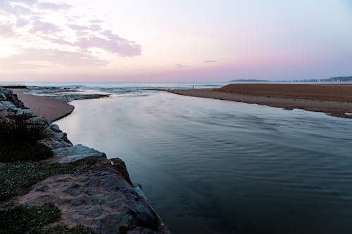 Free Peaceful scene of a Sydney beach at dawn with calm waters and pastel skies, ideal for serene landscapes. Stock Photo
