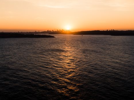 Captivating view of Sydney skyline during sunset with ocean reflections.