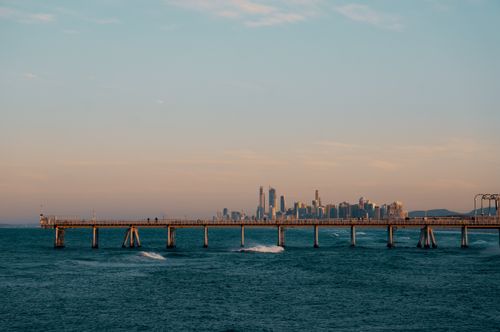 Free Beautiful view of Sydney skyline with a pier extending over the ocean during sunset. Stock Photo
