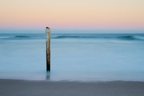 Rusty Metal Pole on the Beach During Sunset