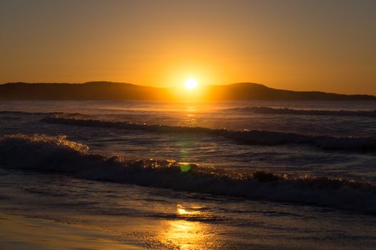 Capture the tranquility of a stunning sunset over waves at an Australian beach.