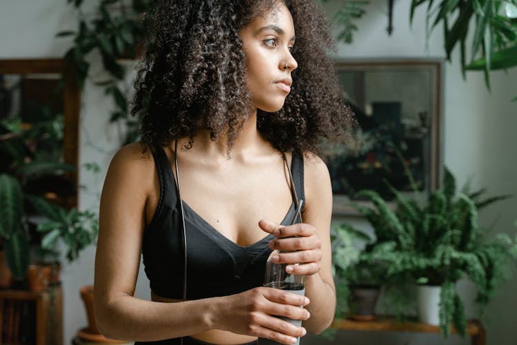 A Woman In Black Sports Bra Holding A Bottle Of Water