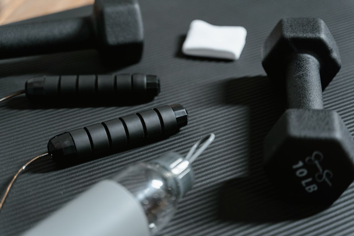 Dumbbells, jump rope and workout accessories arranged on a training mat