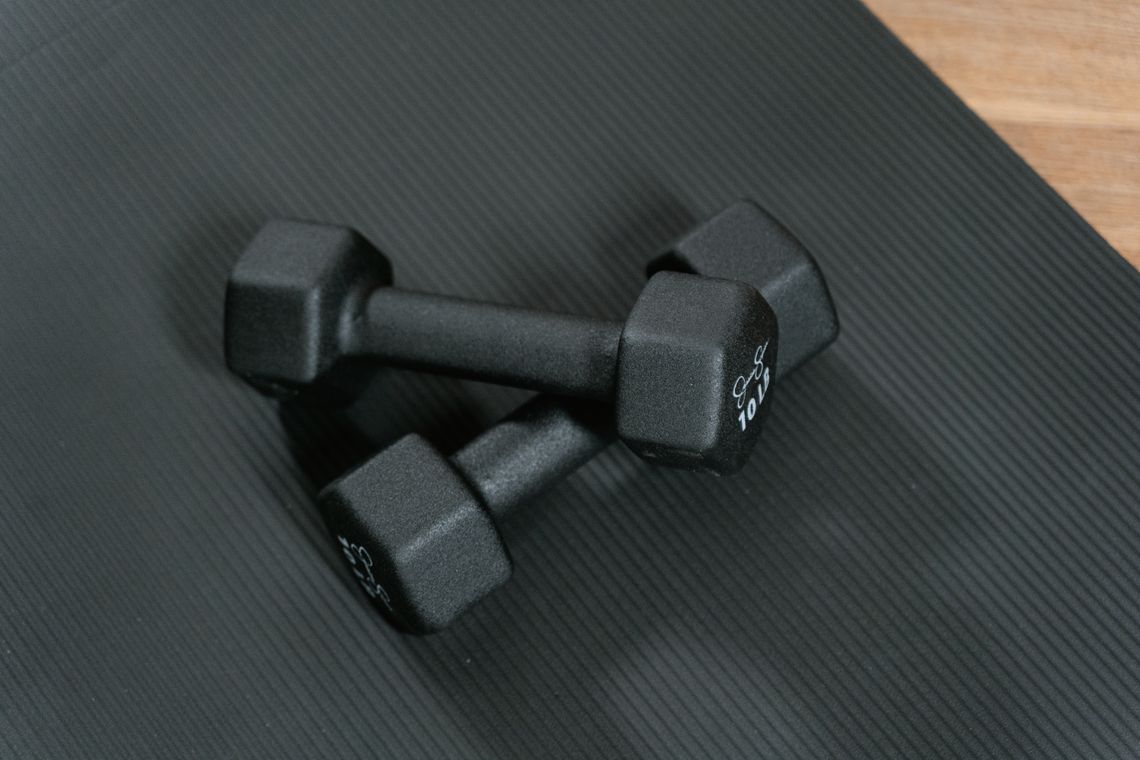 Real black dumbbells placed on an exercise mat for compact home strength training