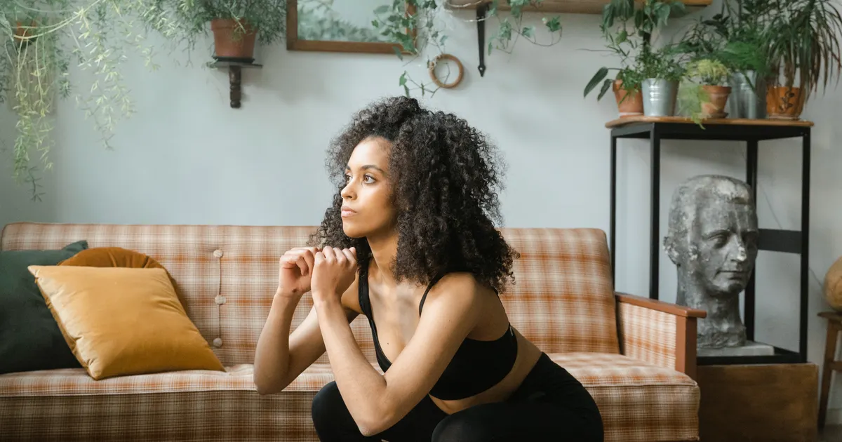 Woman doing a squat on a mat in her living room