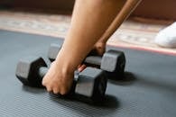 Person Holding Black Dumbbells