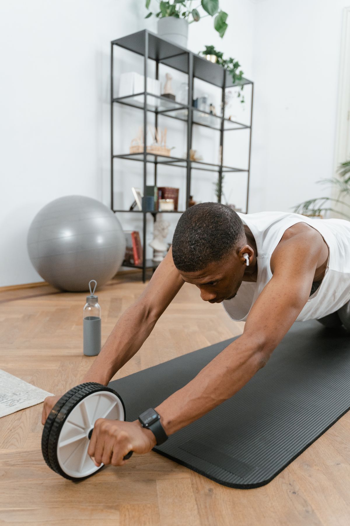 Man doing an ab wheel exercise on a gym floor