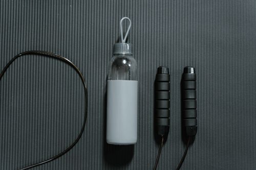 Free Flatlay of a water bottle and jump rope on a yoga mat, highlighting fitness essentials. Stock Photo