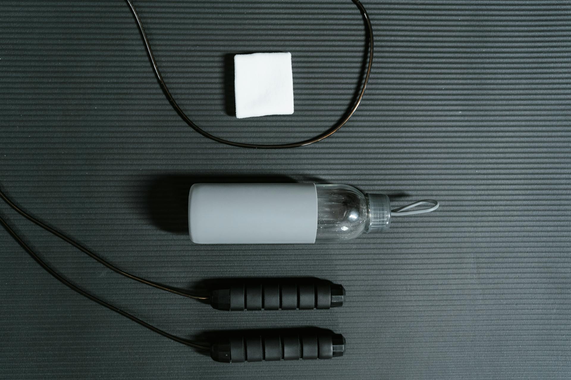 A Water Bottle and a Jump Rope on Black Surface