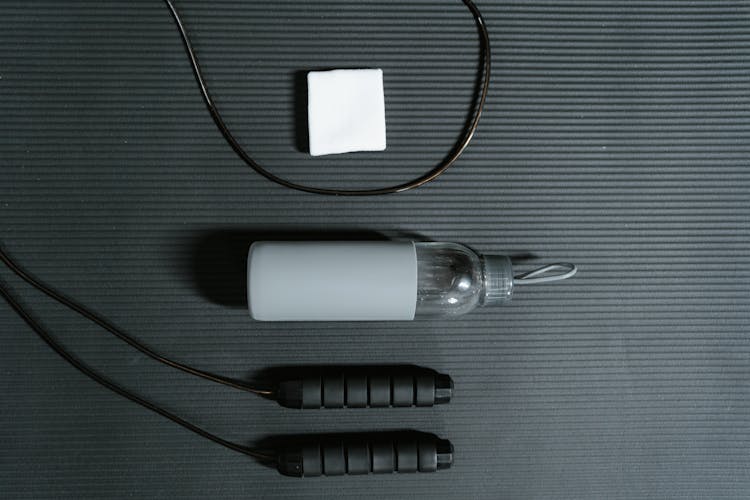 A Water Bottle And A Jump Rope On Black Surface