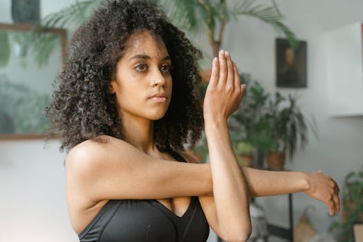 Woman doing a stretching exercise indoors surrounded by plants.