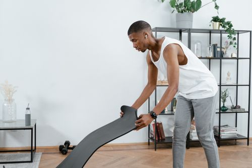 Free African American man preparing for a workout with yoga mat at home. Stock Photo