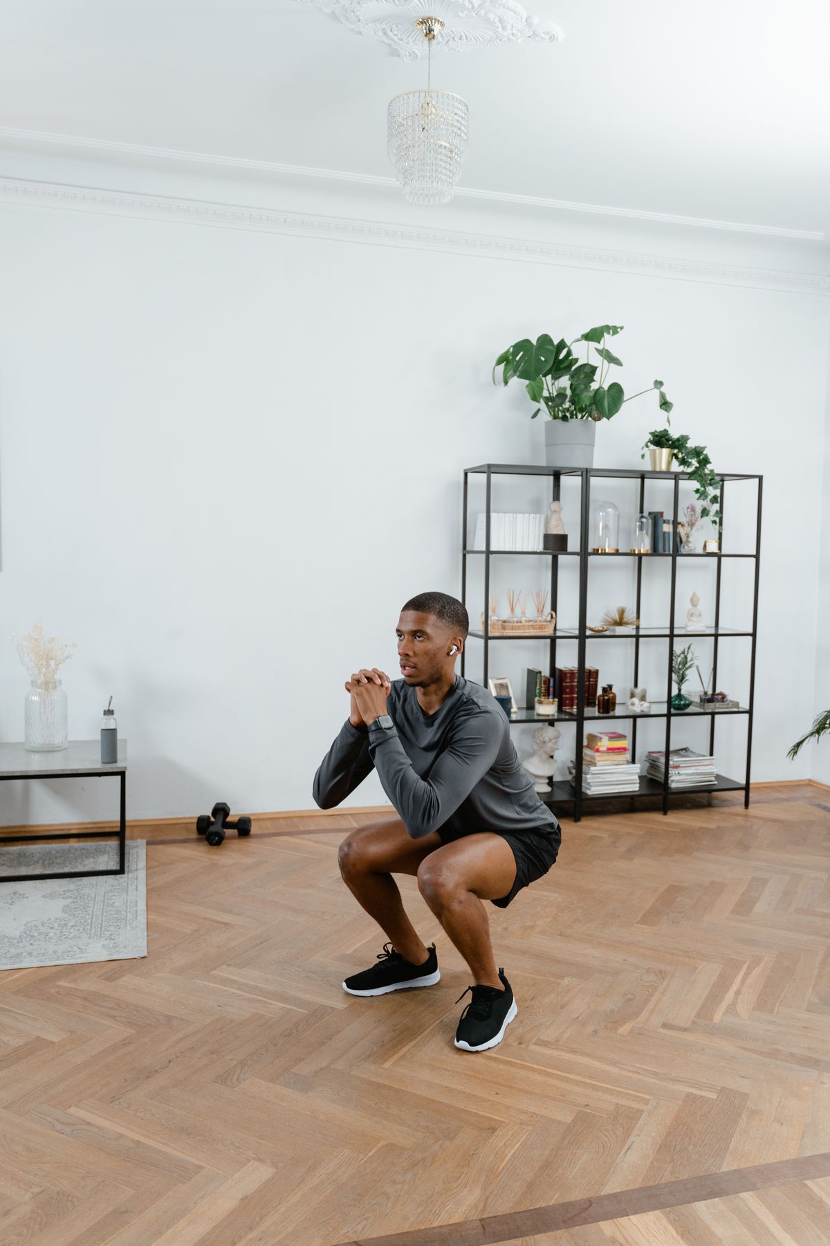 Man performing bodyweight squats at home in athletic wear