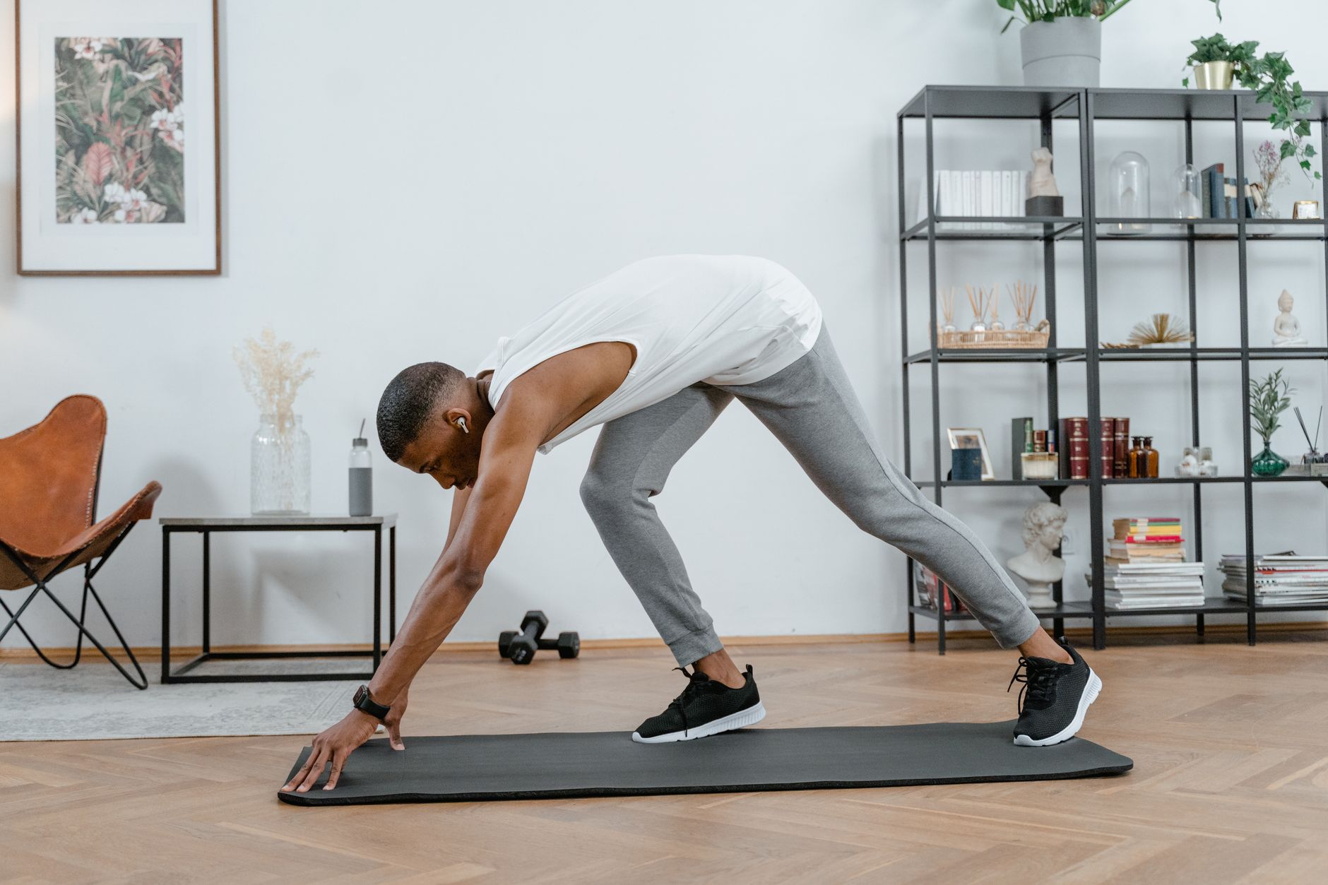 Adult black man stretching on yoga mat indoors, embracing fitness and healthy lifestyle.