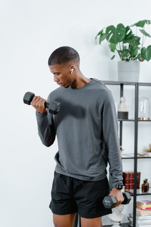 Free African American man lifting dumbbells in a modern living space, focusing on fitness. Stock Photo