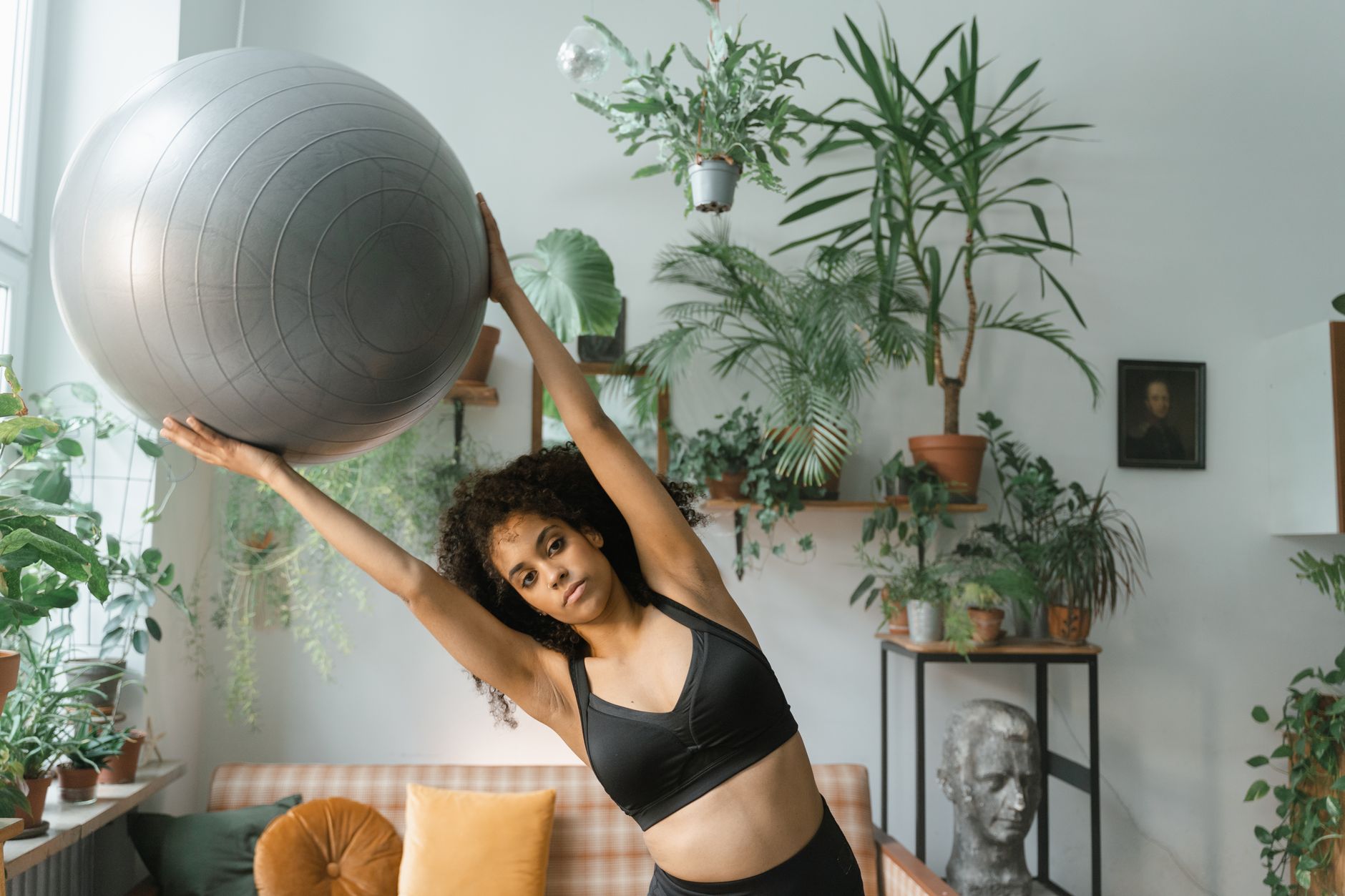 Woman putting on ankle weights before a home workout, kneeling on a yoga mat in bright natural light