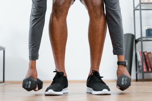 Free Person engaging in a home workout lifting dumbbells, promoting fitness and healthy living. Stock Photo