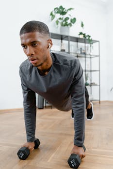Young man in athletic wear doing a workout with dumbbells indoors.