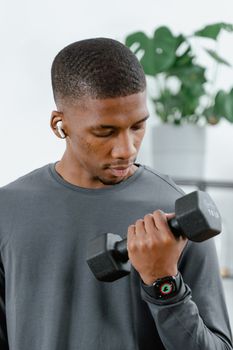 African American man lifting dumbbell indoors, exemplifying fitness and a healthy lifestyle.