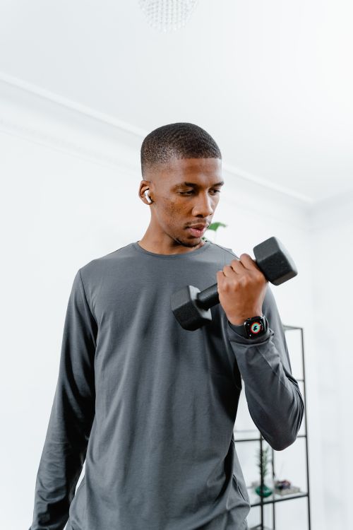 Free African American man lifting dumbbell indoors while exercising for fitness. Stock Photo