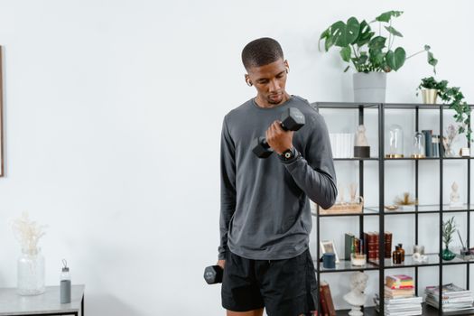 Young man exercising with dumbbells indoors for a healthy lifestyle.