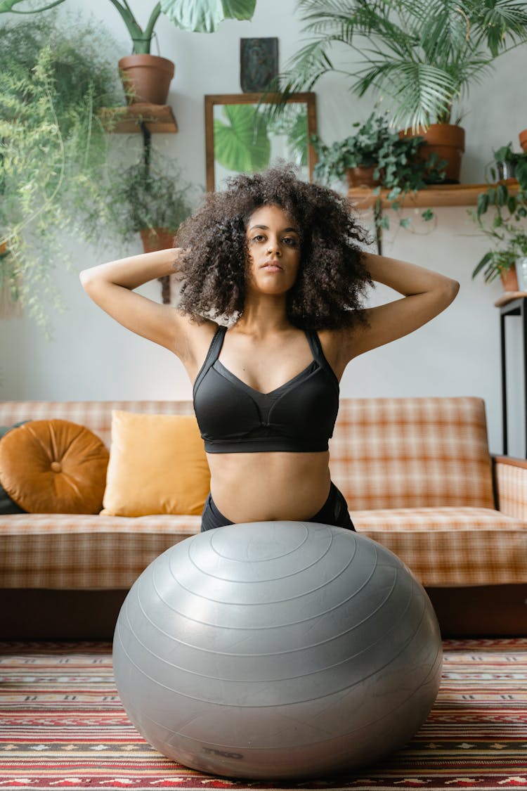 Pretty Woman In Black Sports Bra Using An Exercise Ball