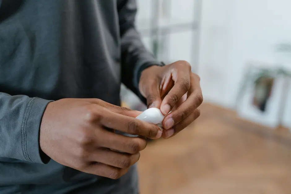 Gros plan sur les mains tenant un appareil auditif 100% Santé remboursé avec ses accessoires.