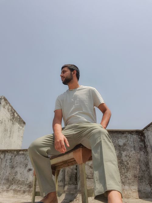 Free A young man in casual clothing sitting outdoors on a sunny day, posing confidently. Stock Photo