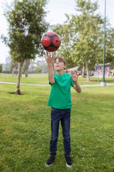 A boy in a green shirt plays with a soccer ball in a park. Bright and lively setting.
