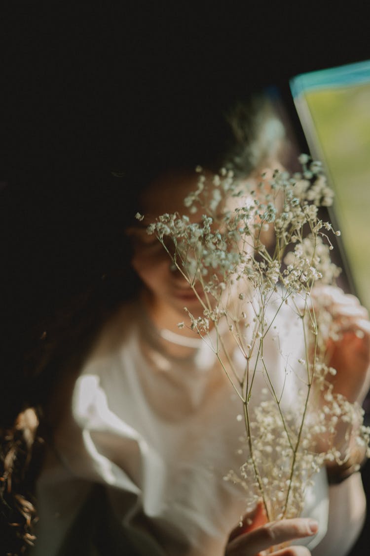 Person In White Blouse Holding Baby S Breath Flowers