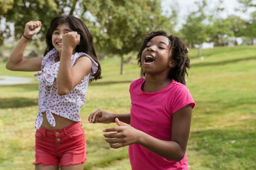 Free Two cheerful girls having fun outdoors on a sunny day, celebrating friendship. Stock Photo