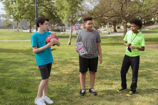 Three boys enjoying a sunny day in a park, playing and interacting together.
