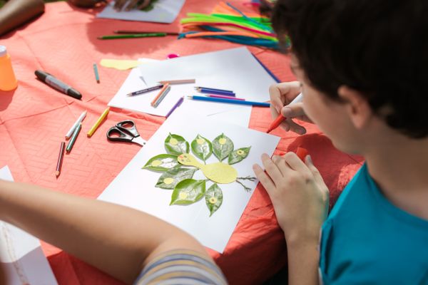A child creating an art piece with leaves outdoors