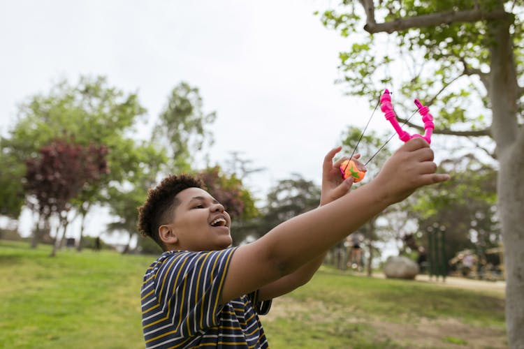 A Boy Playing With A Toy Slingshot Outdoors