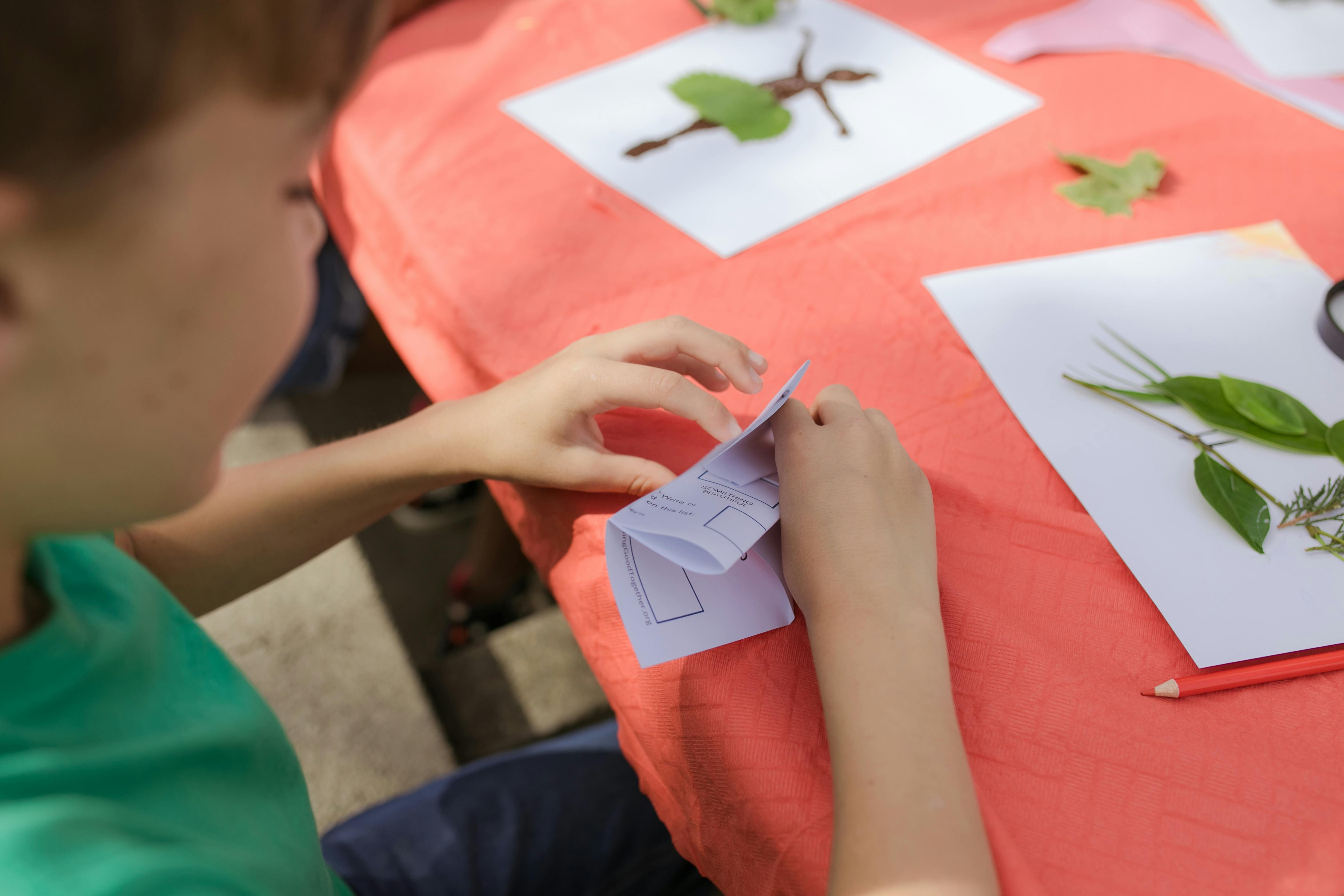 person holding white printer paper with green frog drawing