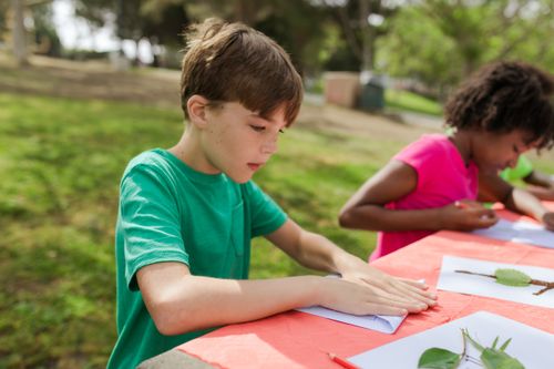 Free Young kids engage in outdoor crafting activities during summer camp, learning and having fun. Stock Photo