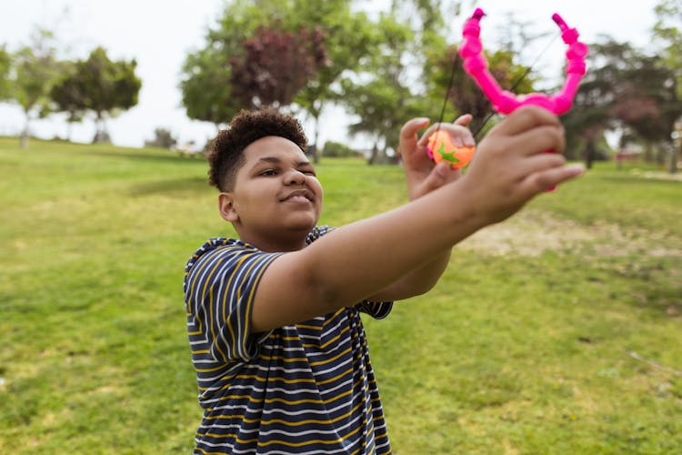 Kid Shooting A Slingshot